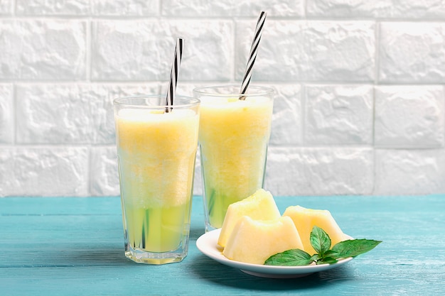 Limonata al melone, frullato con ghiaccio e basilico in un bicchiere sul tavolo grigio. Bevanda rinfrescante e disintossicante estiva Stile rustico