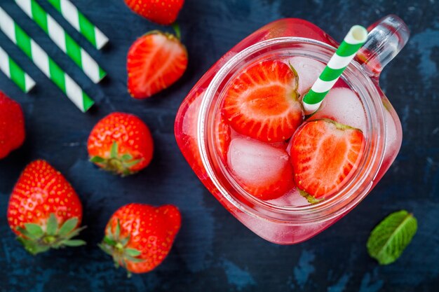 Limonata alla fragola con ghiaccio in barattolo di vetro su un tavolo di legno