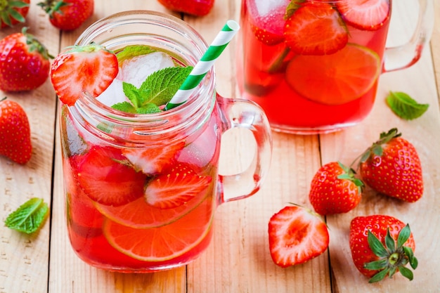 Limonata alla fragola con lime e ghiaccio in barattolo di vetro su un tavolo di legno