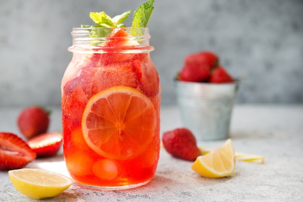 Limonata alla fragola fatta in casa con ghiaccio in un barattolo, cocktail estivo freddo, fuoco selettivo