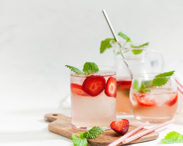 Limonata alla fragola rinfrescante fatta in casa in bicchieri e brocca con fragole fresche e foglie di menta