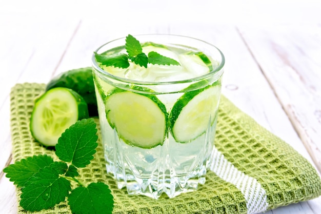 Limonata con cetriolo e menta in un bicchiere su un tovagliolo verde su uno sfondo di assi di legno
