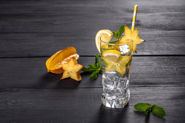 Limonata con limone, menta e cubetti di ghiaccio in vetro su superficie in pietra grigia