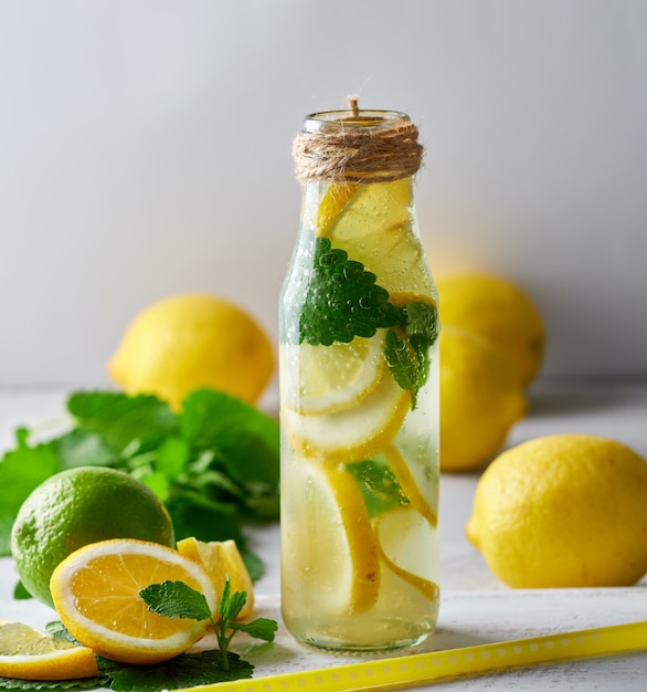 limonata con limoni, foglie di menta, lime in una bottiglia di vetro