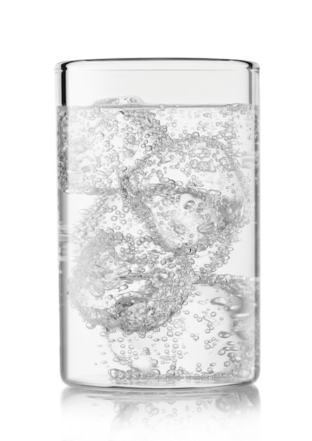 Limonata di acqua frizzante minerale con cubetti di ghiaccio in vetro highball su sfondo bianco