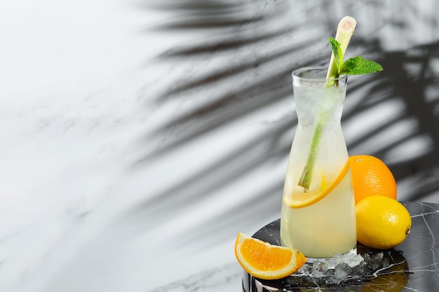 Limonata di agrumi con citronella e ingredienti vicino al tavolo di marmo. limonata in caraffa con ghiaccio