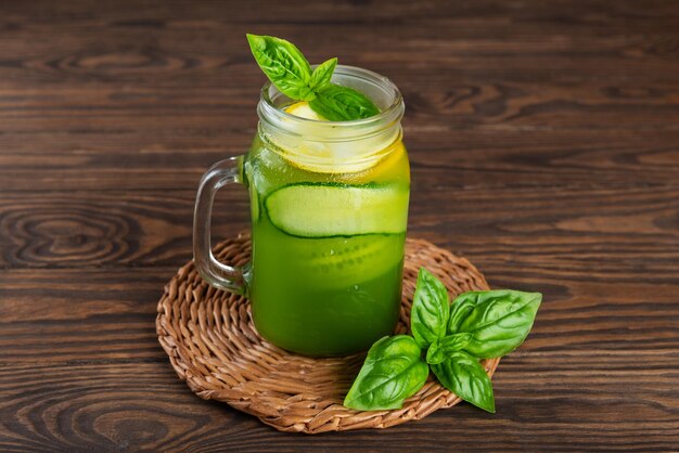 Limonata di cetriolo fresco con basilico e limone in una tazza di vetro sul tavolo di legno