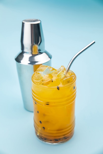 Limonata di frutto della passione in un bicchiere da bar con ghiaccio su un tavolo blu