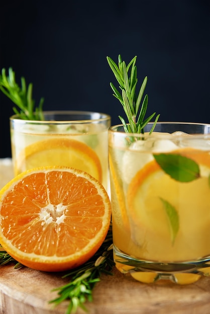 Limonata fatta in casa con arancia e rosmarino bicchiere di cocktail estivo su sfondo scuro