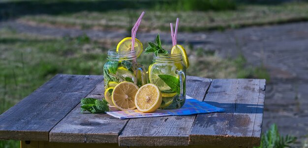 Limonata fatta in casa con limone, menta e ghiaccio in bicchieri, sul tavolo di legno, all'aperto.