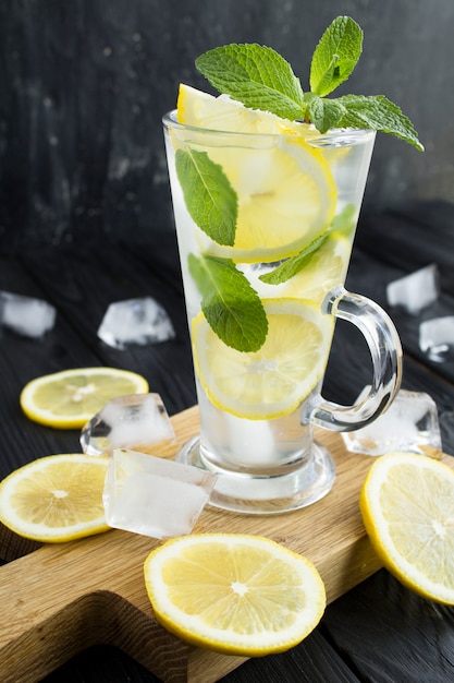 Limonata fredda con limone e menta nel bicchiere su sfondo scuro