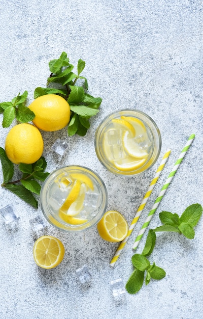 Limonata fredda con limone, menta e ghiaccio su uno sfondo di cemento.