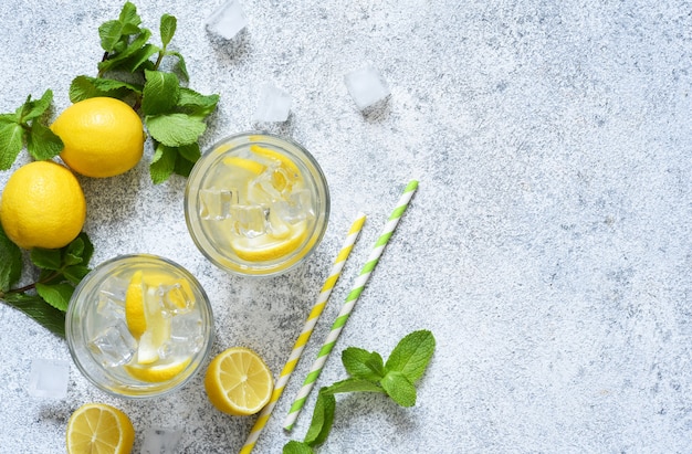 Limonata fredda con limone, menta e ghiaccio su uno sfondo di cemento.