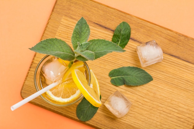 Limonata fredda rinfrescante con ghiaccio e fette di limone decorata con foglie di menta in un bicchiere alto