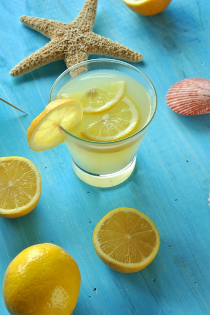 Limonata fresca con stelle marine e conchiglie sul tavolo blu