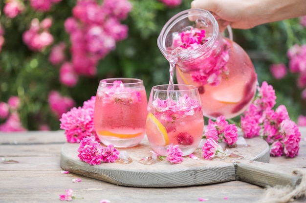 Limonata fresca di rose con ghiaccio e rose fresche sul giardino naturale