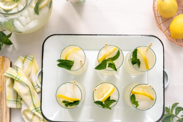 Limonata tradizionale con una fetta di limone fresco e menta con cannuccia di carta nel bicchiere.