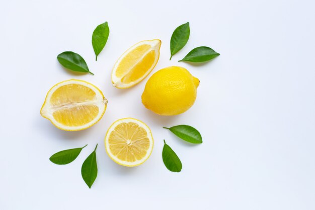 Limone e fette con foglie isolate su bianco.