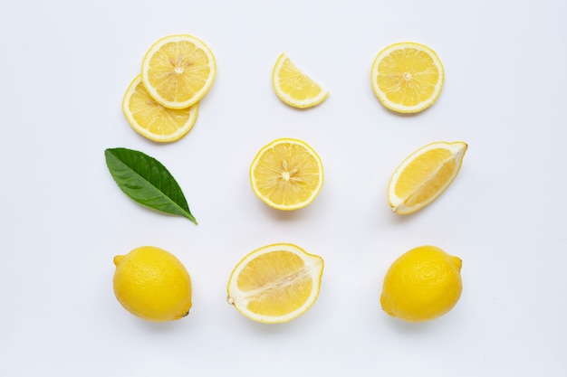 Limone e fette con foglie isolate su bianco.