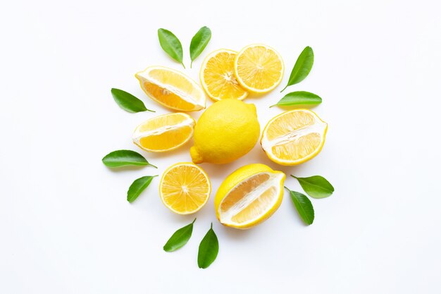 Limone e fette con le foglie isolate su bianco.