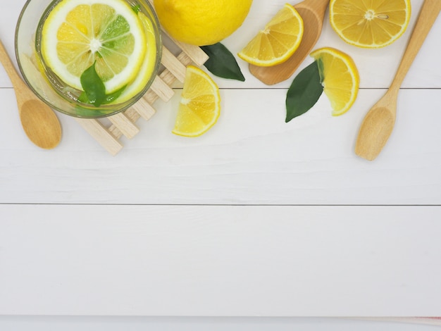 Limone fresco in acqua e fetta di limone su fondo di legno bianco