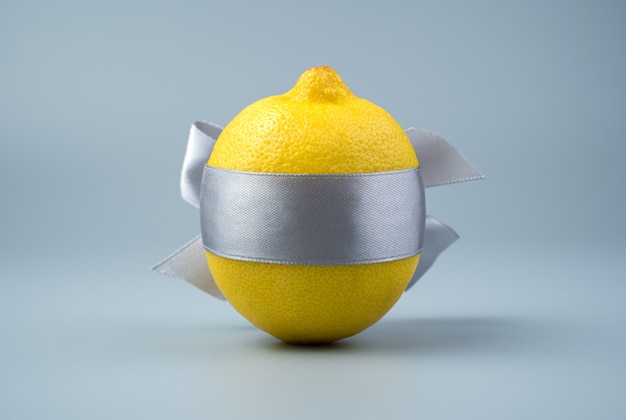 Limone legato con un nastro su uno sfondo grigio.