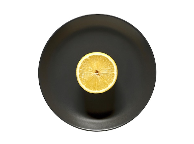 Limone tagliato su piatto rotondo grigio scuro isolato su sfondo bianco con tracciato di ritaglio