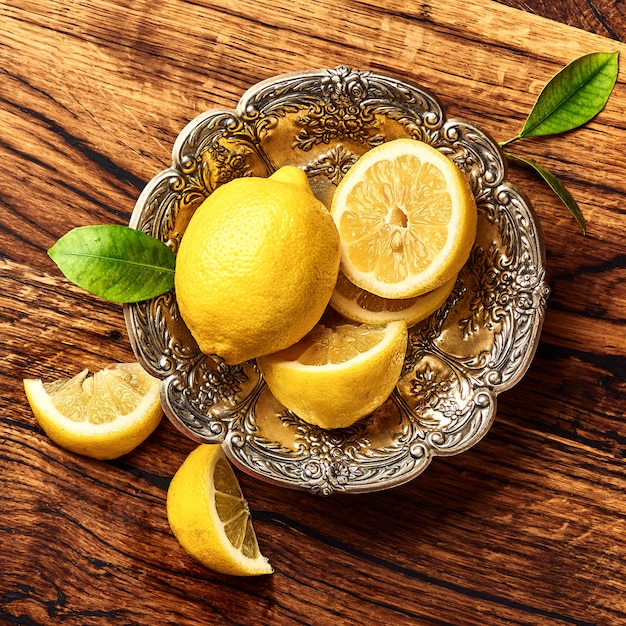 Limoni con le foglie sulla tavola di legno di quercia. Vista dall'alto di frutta.