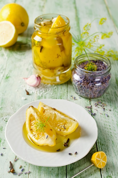 Limoni conservati con sale, lavanda, aglio e chiodi di garofano su un tavolo di legno e spezie