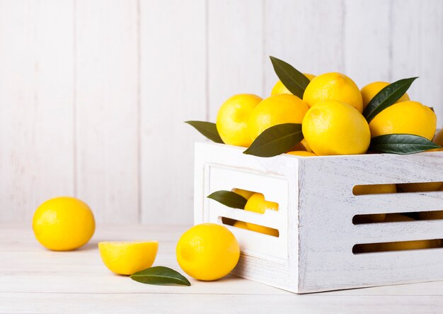 Limoni crudi freschi in scatola di legno bianca con le foglie