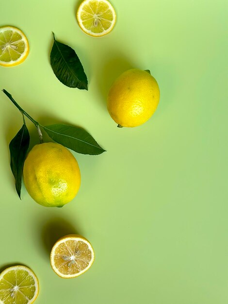 Limoni gialli, luminosi, succosi, maturi con foglie verdi su sfondo verde chiaro, foto per telefono