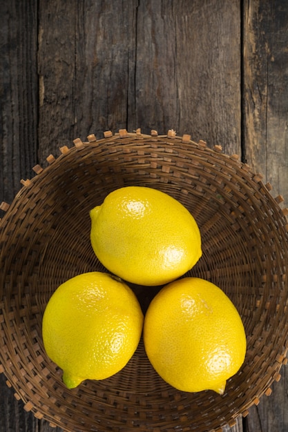 Limoni in piatto di vimini su fondo di legno