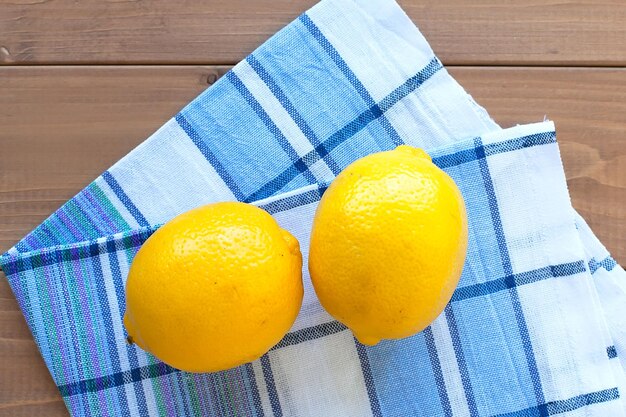 Limoni interi maturi su un tavolo di legno su un asciugamano di cotone prodotti alimentari