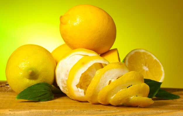 Limoni maturi con foglie sulla tavola di legno su sfondo verde