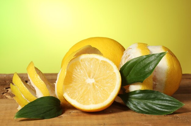 Limoni maturi con foglie sulla tavola di legno su sfondo verde