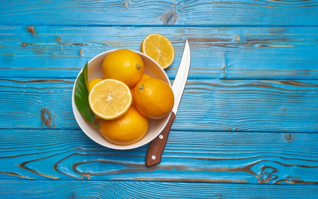 Limoni maturi freschi in ciotola bianca sulla vista superiore del tavolo di legno rustico con lo spazio della copia.