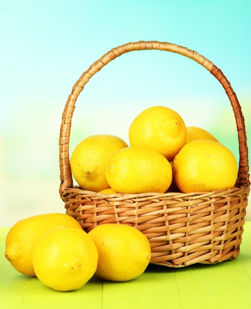 Limoni maturi in cesto di vimini sul tavolo su sfondo luminoso