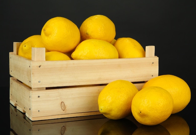 Limoni maturi in scatola di legno isolata sul nero
