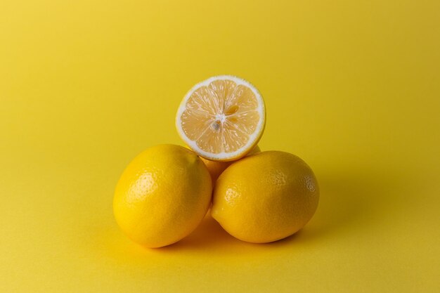 Limoni maturi succosi foglie arancioni e verdi su sfondo giallo brillante Limone frutta agrumi concetto minimo vitamina C Sfondo minimalista estate creativa Vista dall'alto piatta spazio copia