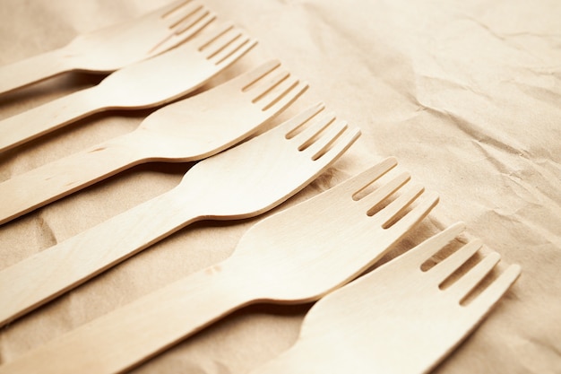 linea diagonale composta da una pila di forchette di legno monouso eco friendly su sfondo di carta. utensili da cucina. concetto ecologico. spazio per il testo