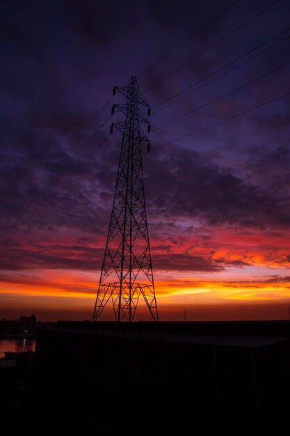 Linea elettrica ad alta tensione torre con bel cielo al tramonto stock foto