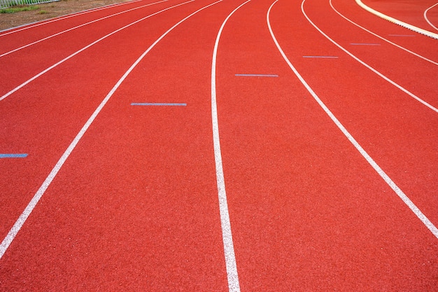 Linee bianche di stadio e struttura di piste da corsa in gomma rossa da corsa.