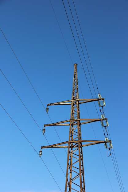 Linee elettriche di fiducia con i cavi sullo sfondo del cielo blu con nuvole.
