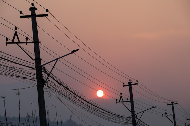 Linee elettriche e pali con il sole che tramonta dietro di loro