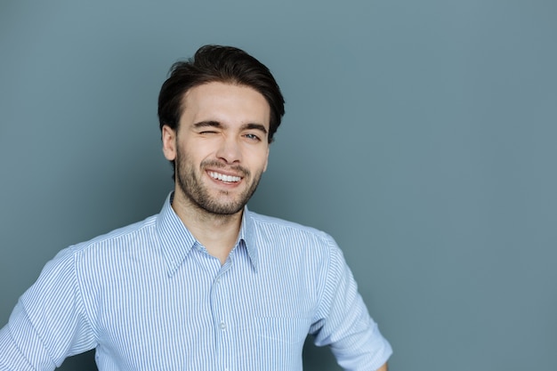 Linguaggio non verbale. Allegro uomo felice positivo sorridente e ammiccante mentre ti guarda