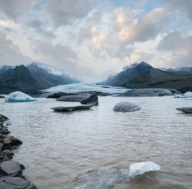 Lingue di ghiacciaio scivola dalla calotta glaciale Vatnajokull o dal ghiacciaio Vatna vicino al vulcano subglaciale Oraefajokull Islanda Laguna glaciale con blocchi di ghiaccio e montagne circostanti