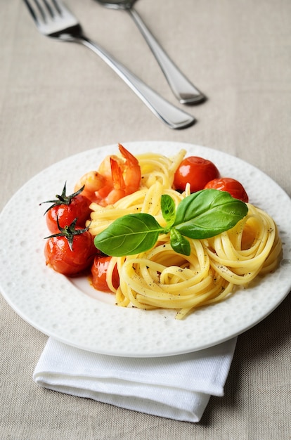 Linguine servito con pomodorini grigliati e gamberi su fondo di lino beige