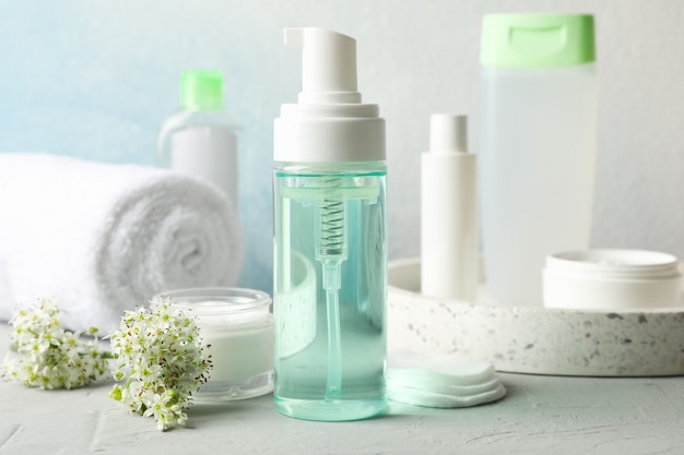 Liquidi per la cura del corpo in diverse bottiglie e fiori di allium su sfondo bianco