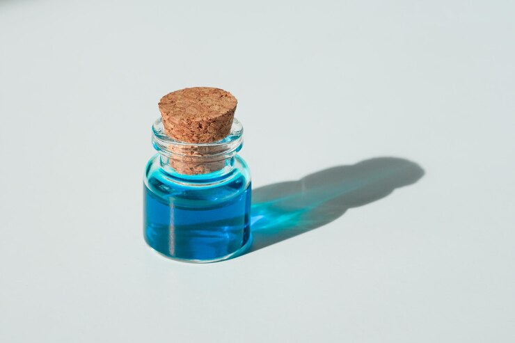 Liquido blu in un vasetto su sfondo bianco. Colorante blu in un becher. Un campione di vernice azzurra.