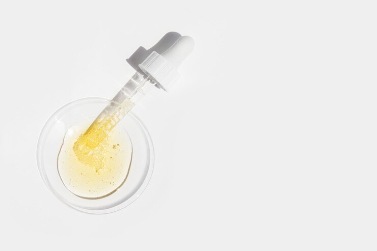 Liquido e pipetta cosmetici gialli su vetro rotondo su sfondo chiaro